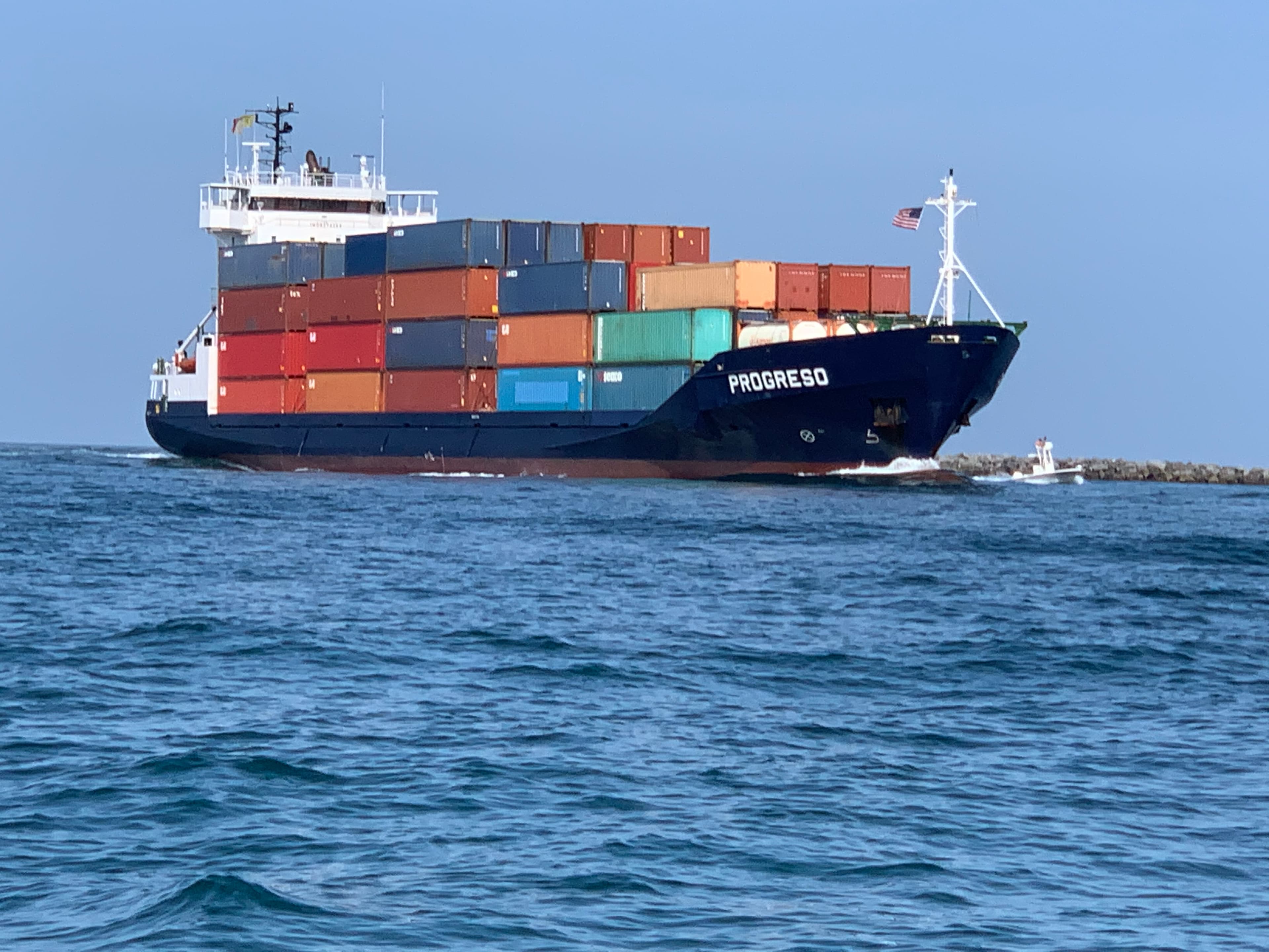 Large blue container ship named Progreso carrying colorful cargo containers across the open ocean.