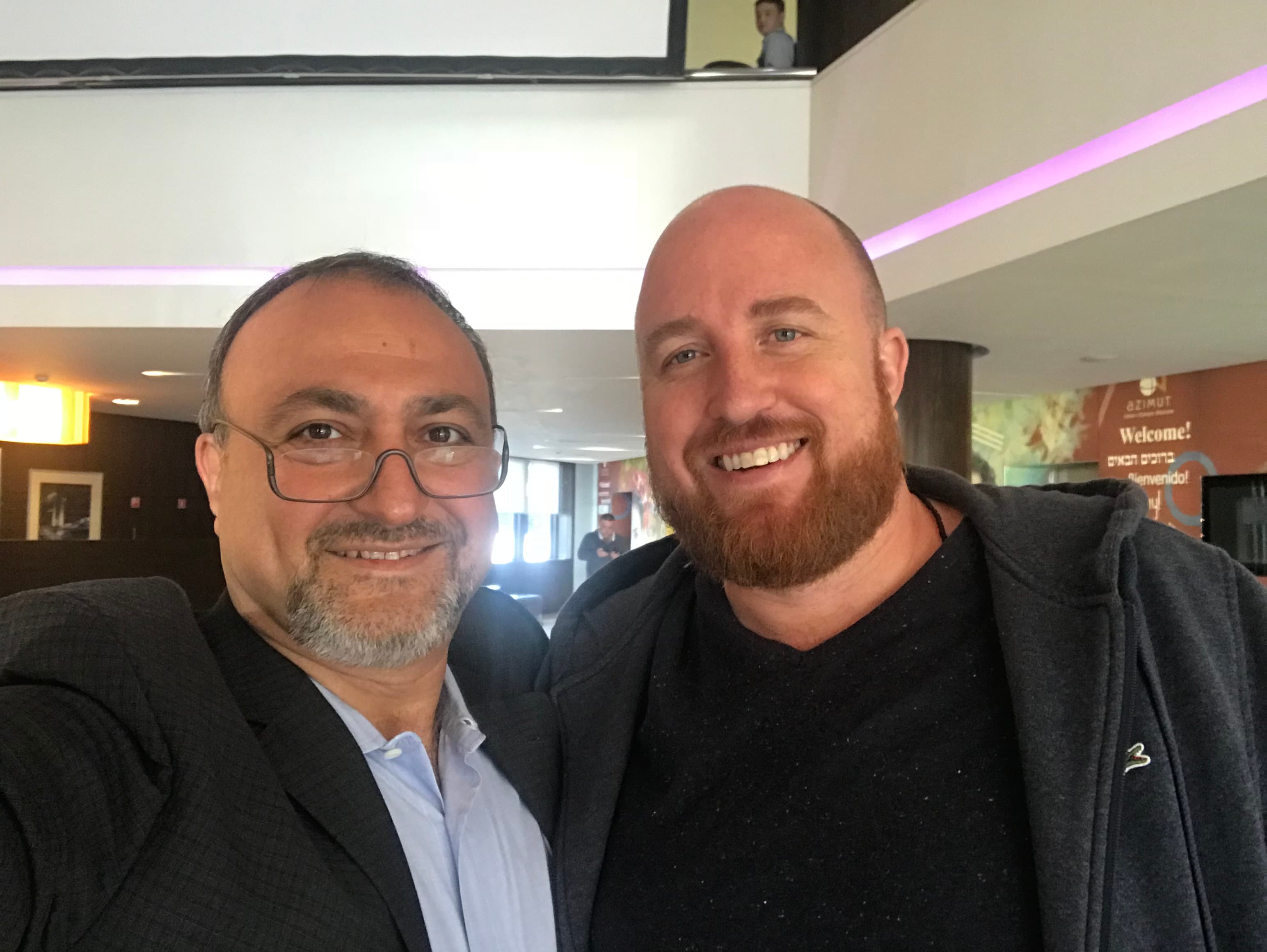Upside-down selfie of two smiling men, one with a red beard and one with glasses.
